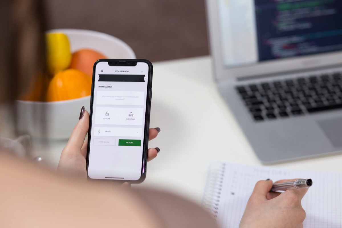 A person using an iPhone to interact with integrated AI features on a clean desk.